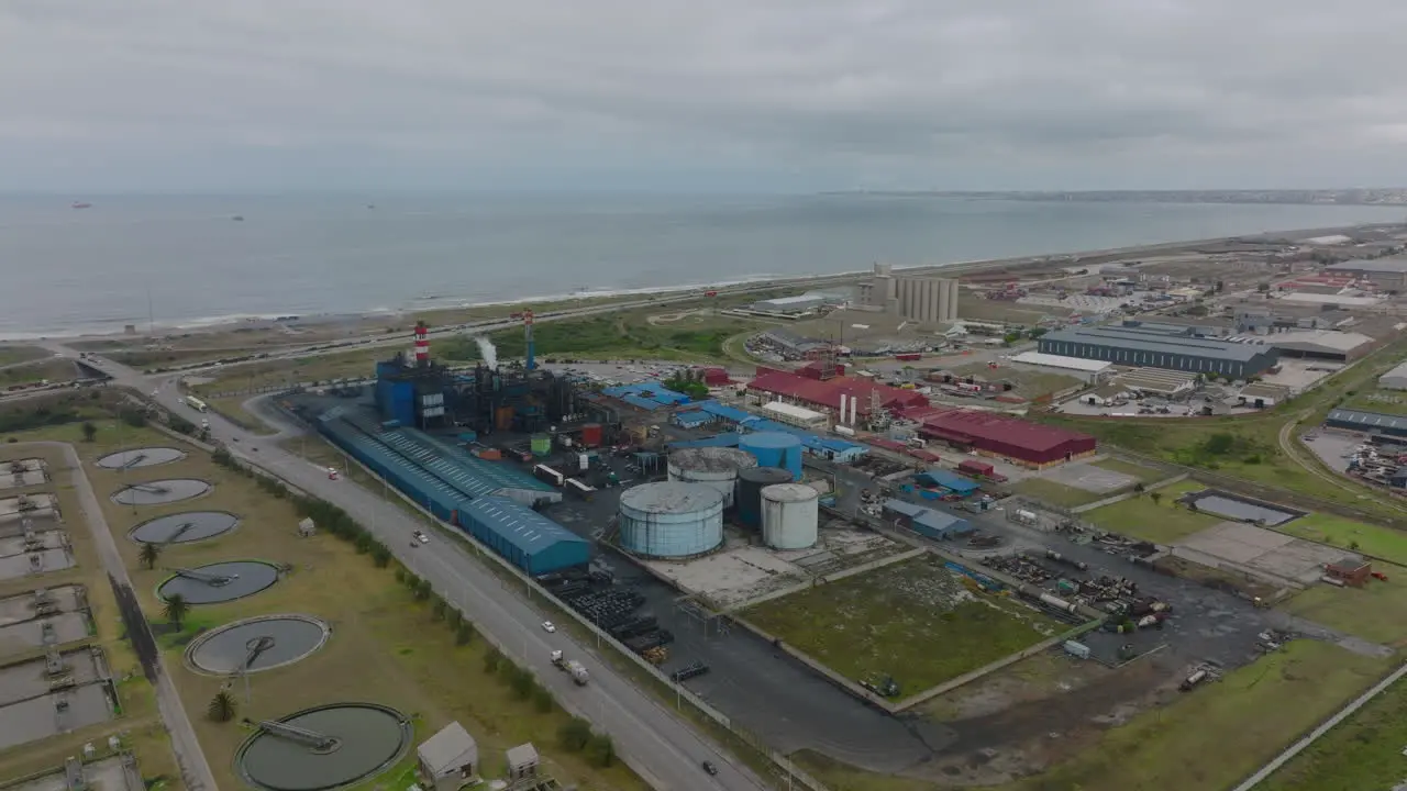 Panoramic aerial view of industrial site at seaside Slide and pan shot of chemical factory with large cylindrical tanks and chimneys Port Elisabeth South Africa