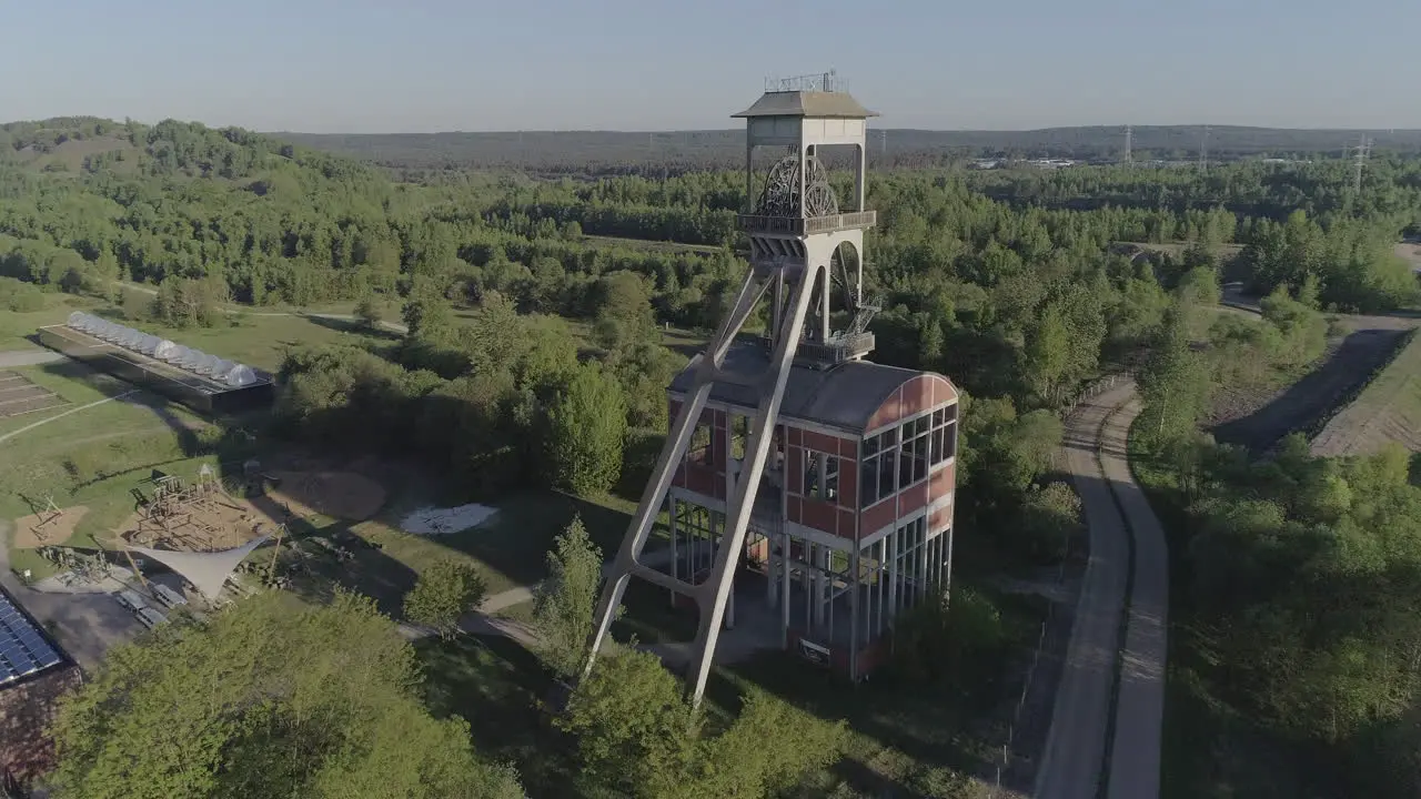 Flyby aerial shot of an old mine shaft tower in a forest background