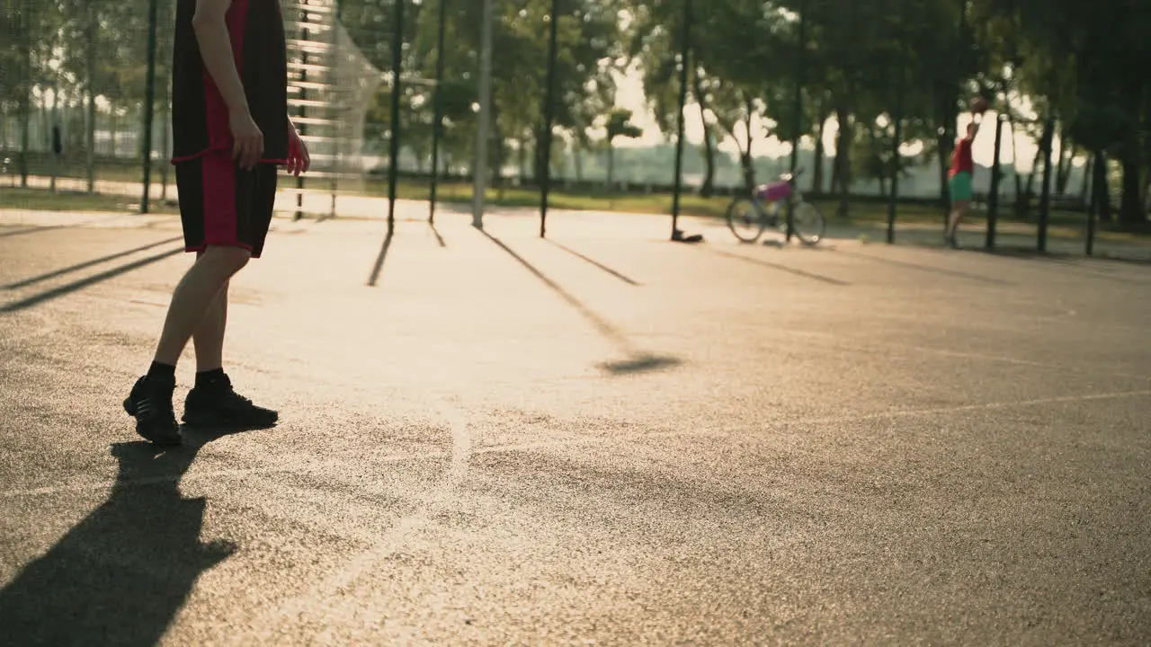 Skillfull Male Basketball Player Dribbling Ball Against Opposing Defender While Playing Streetball Game At Urban Court At Sunset