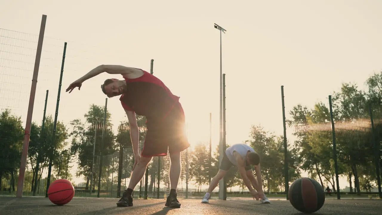 Concentrated Male Basketball Players Stretching In Outdoor Basketball Court 1