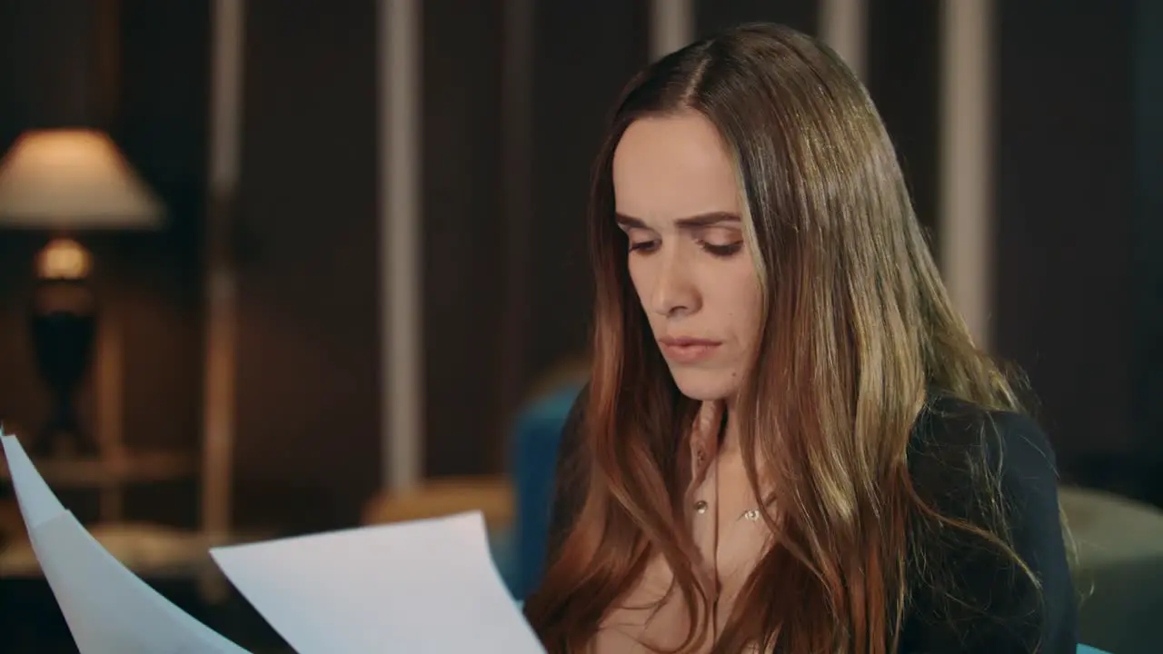 Serious businesswoman reading paper documents in office