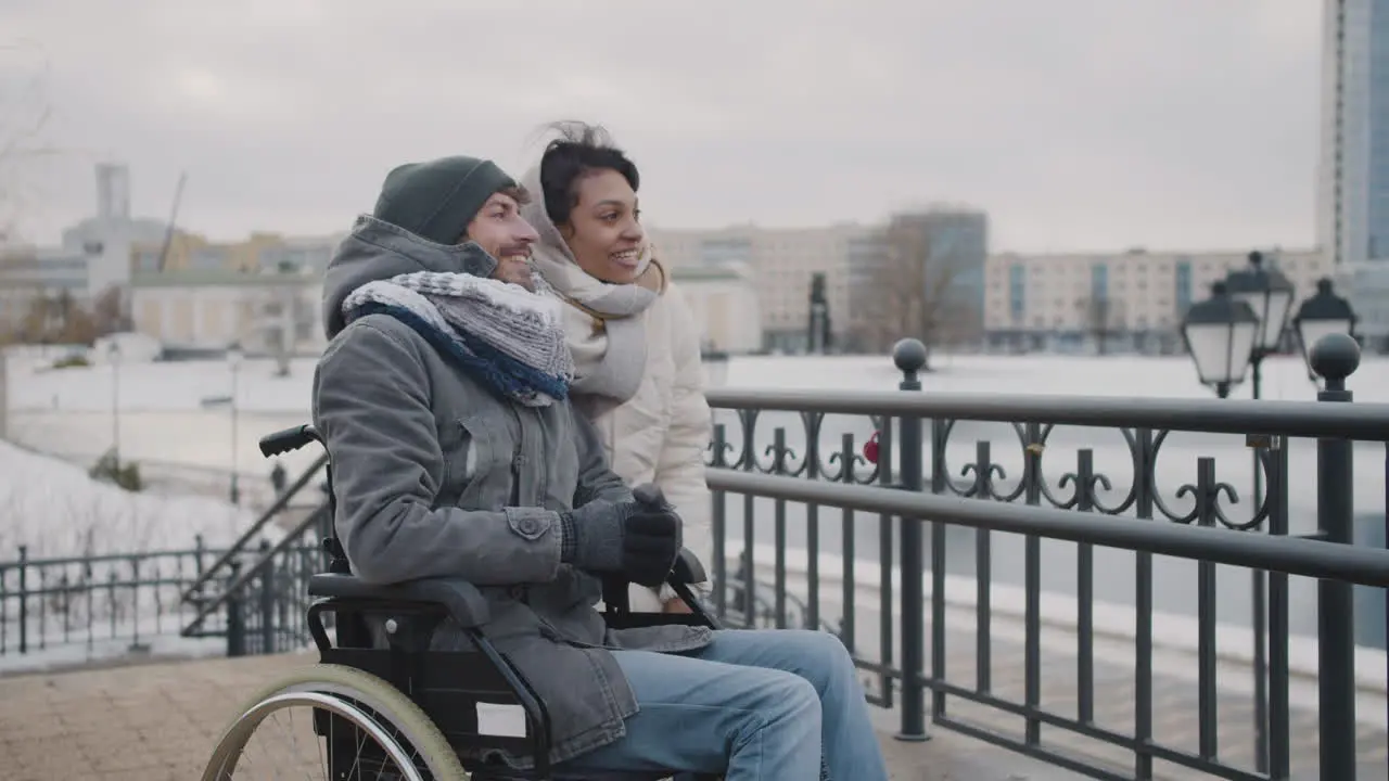 Muslim Woman And Her Disable Friend Looking At Something In The Distance In City In Winter 5