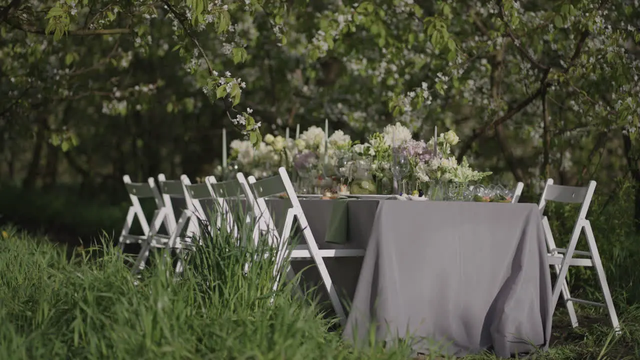 dinner table with flower decoration in blooming garden in spring day romantic open-air event and catering