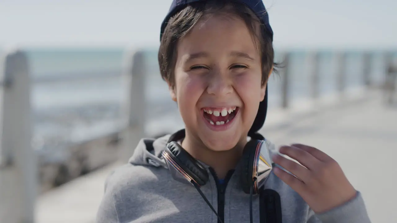 portrait of young little boy laughing cheerful enjoying summer day on vacation seaside beach wearing hat