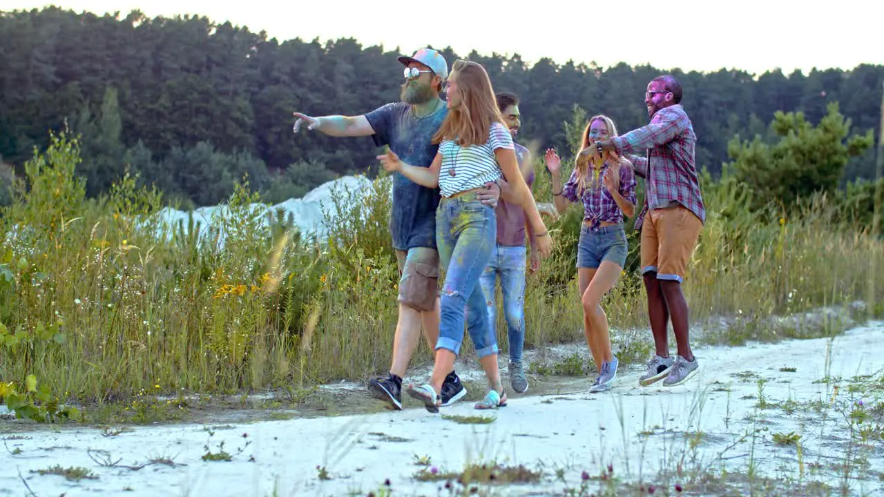 Company Of Young Cheerful Multietnic Friends Girls And Boys Walking Outdoor At The Nature And Laughing During Holi Festival