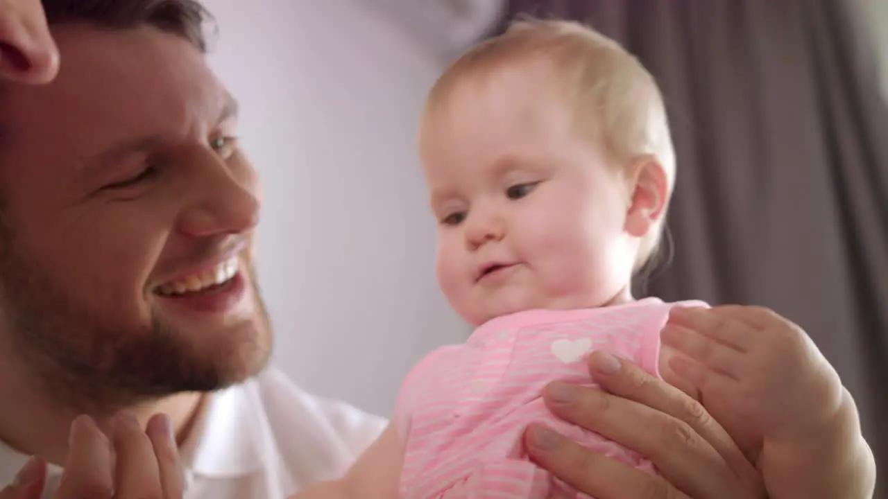 Adorable baby girl in father embrace Portrait of infant play with mom and dad