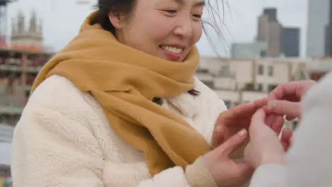 Young Asian Couple With Romantic Man Proposing To Woman Against City Skyline 5