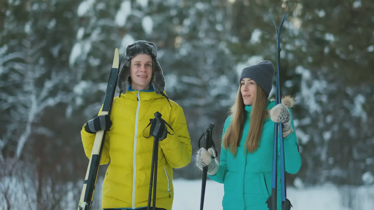 Full length portrait of active young couple enjoying skiing in snowy winter forest focus on smiling woman in front copy space