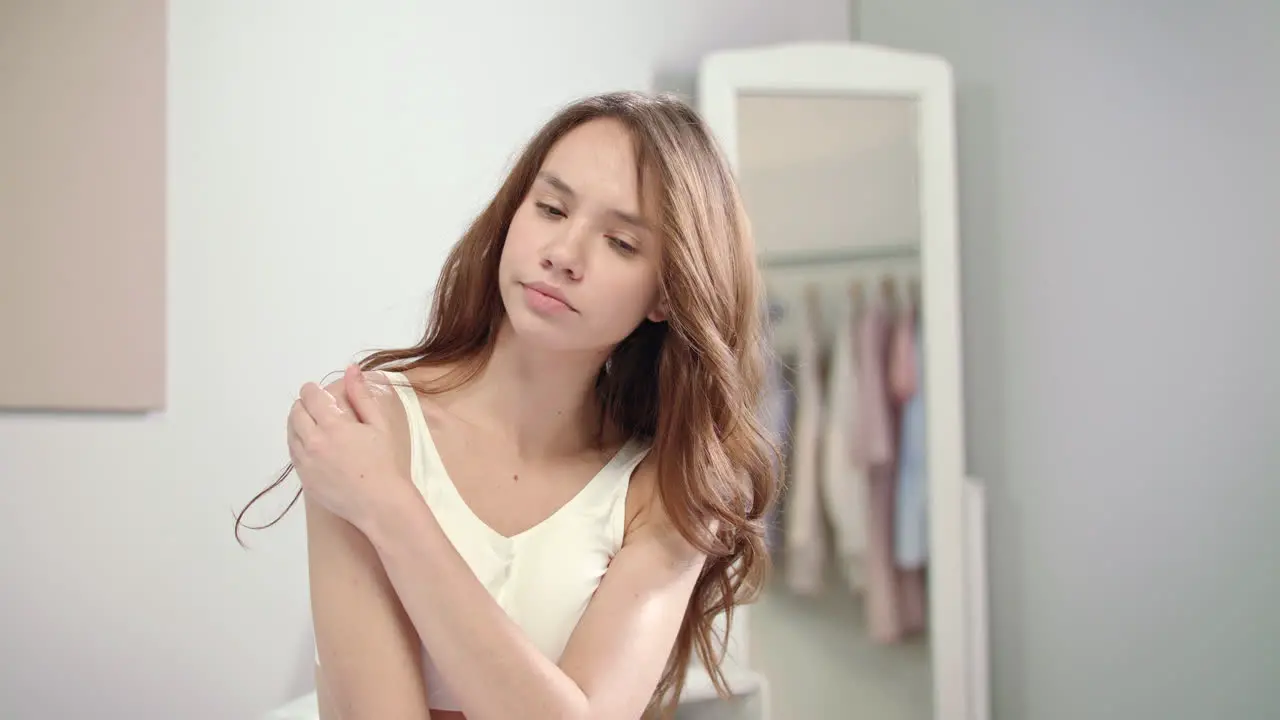 Beautiful girl applying medical lotion on illness shoulder Woman body care