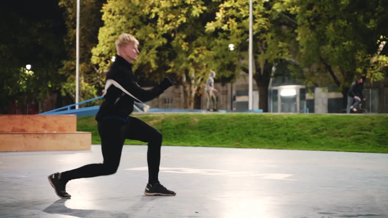 Sportive Blond Man Stretching Legs Doing Lunges Before Training In The Park At Night