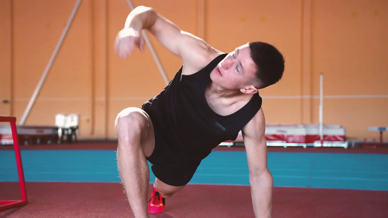 Zoom In Camera Shot Of A Handsome Young Sportsman Warming Up And Stretching In An Indoor Sport Facility