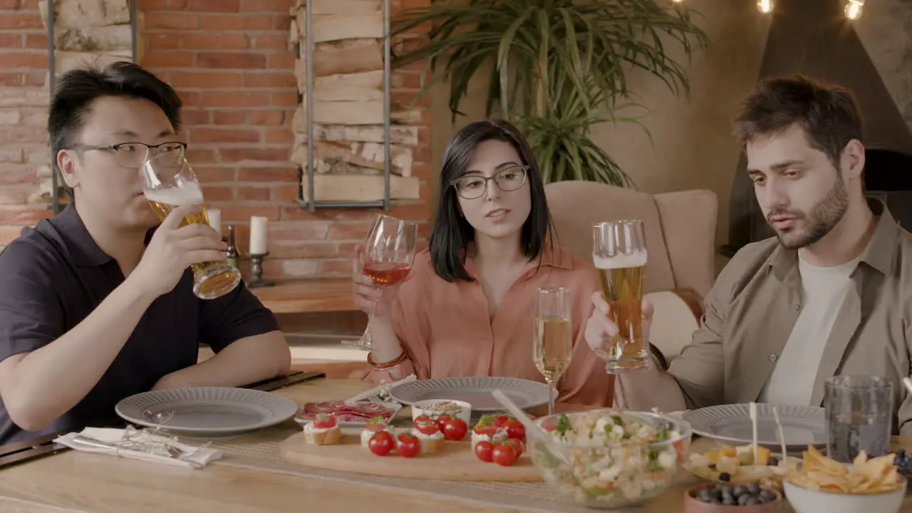 A Group Of Three Friends Toast With Their Glasses At A Dinner Party