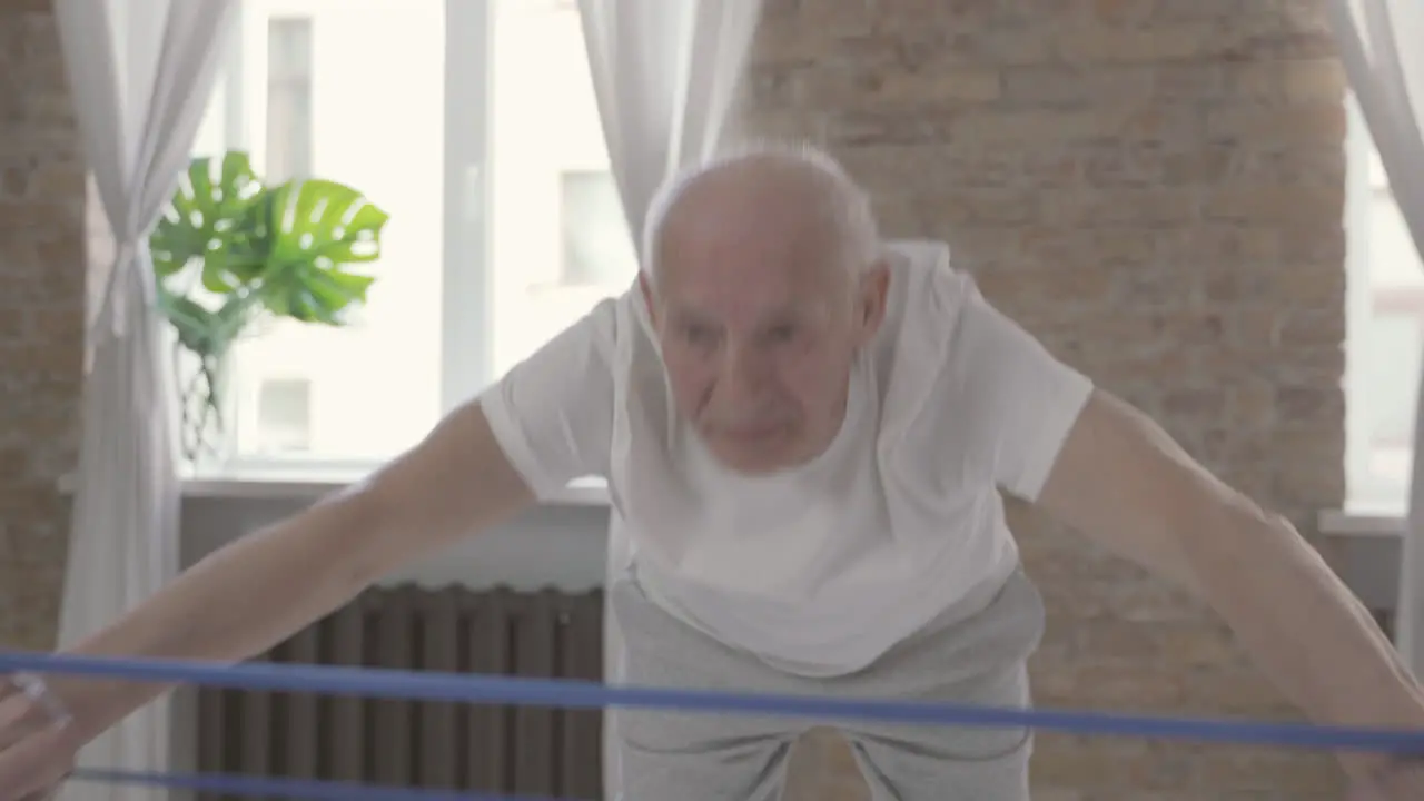 Old Man Using A Stretching Band And Exercising At Home 1