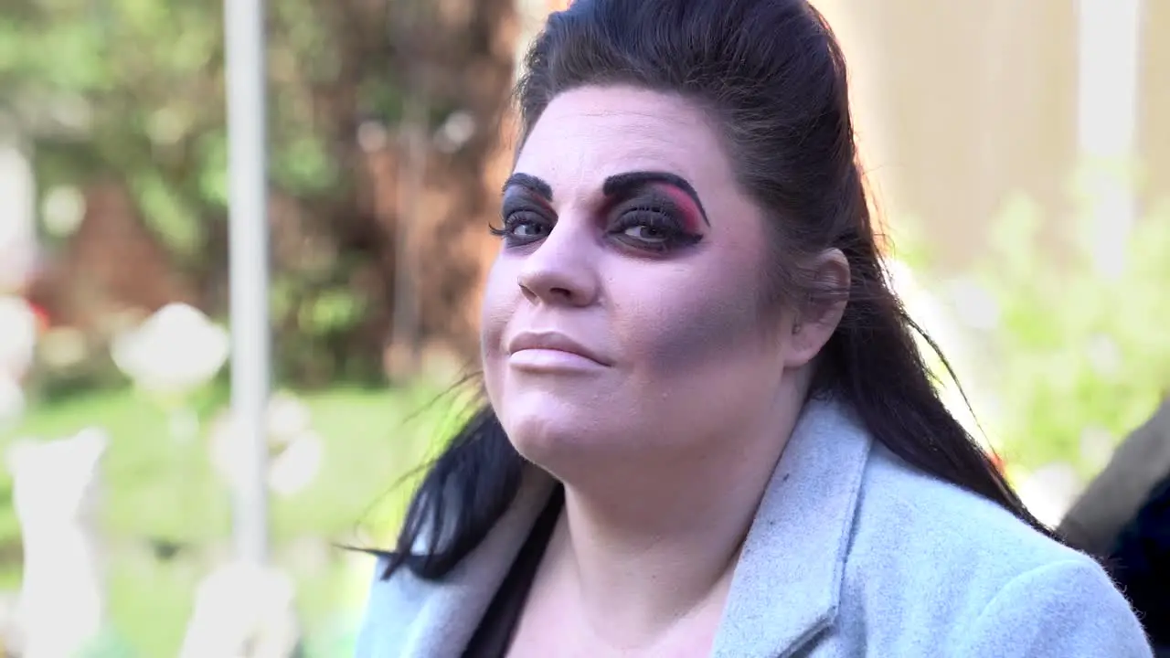 Young lady with dark make up and black hair smiles at the camera slow mo