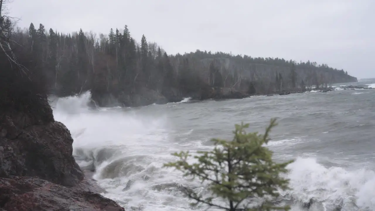 Rough storm waves crashing against rock cliffs on a gloomy day slow motion