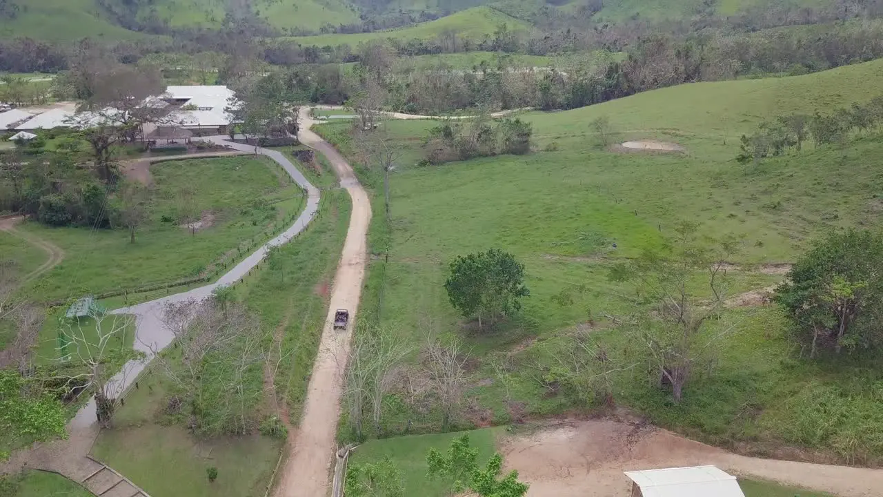 Aerial of a vehicle driving through the barren green landscapes of the Dominican Republic