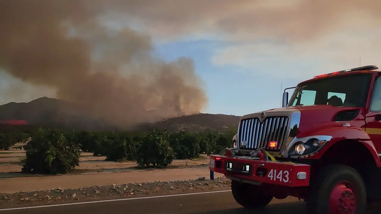 CAL FIRE first responder driving with siren to massive forest fire with dark gray smoke plume