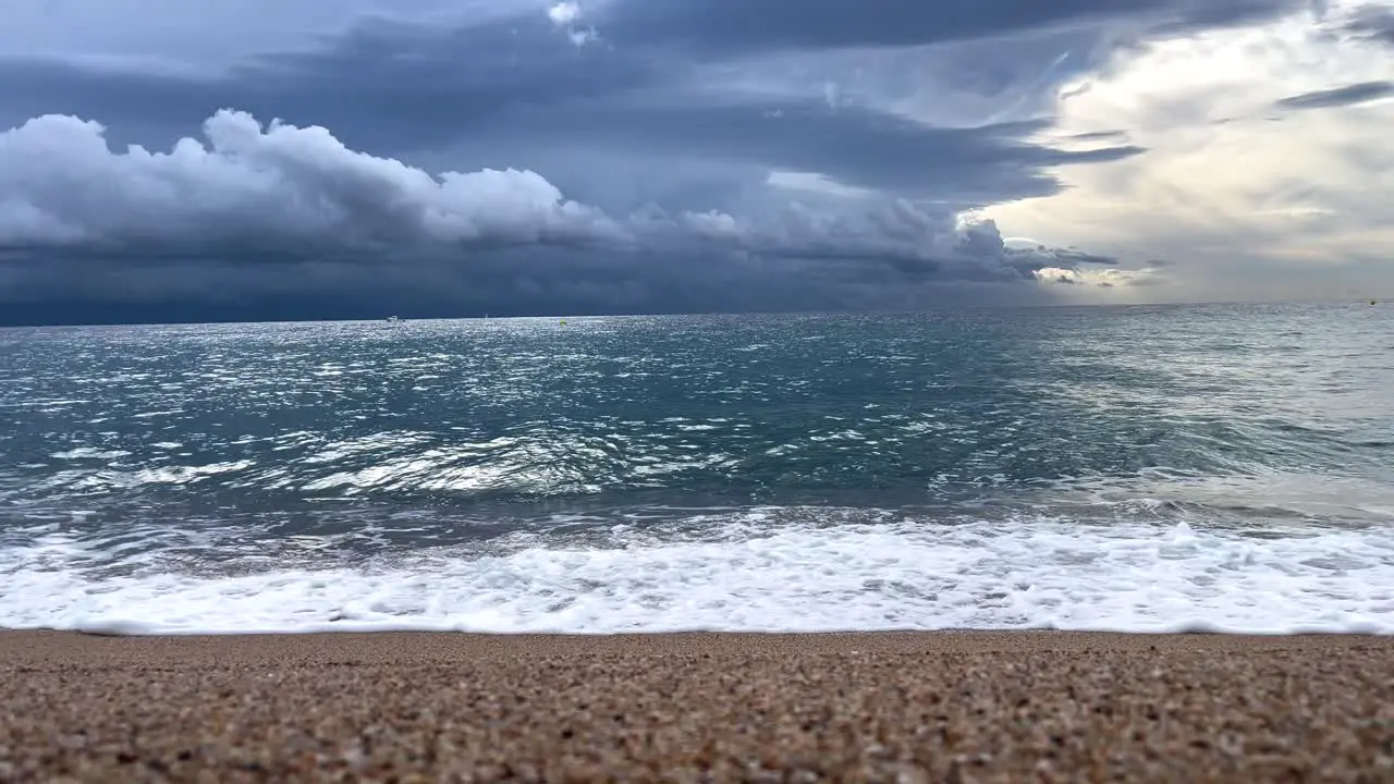 Mediterranean beach with calm water coarse sand and a storm in the background dark gray black sky