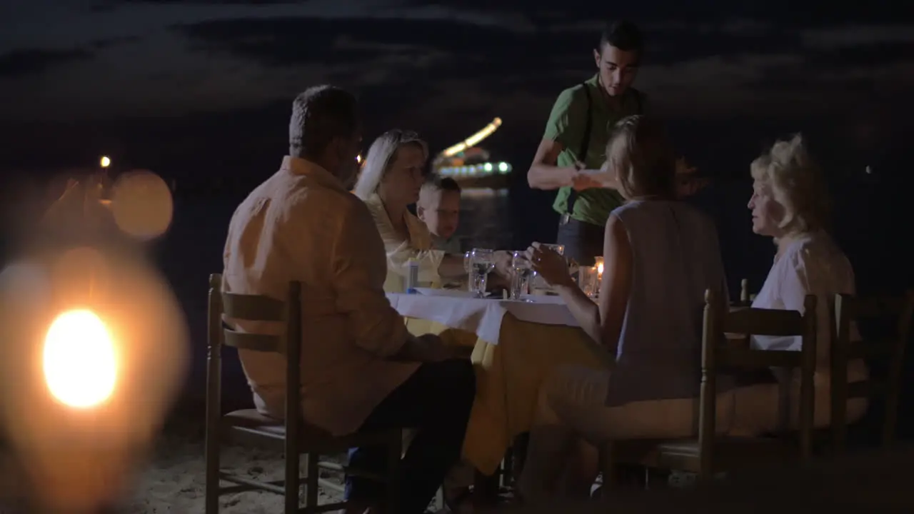 Waiter serving dinner for family in outdoor cafe