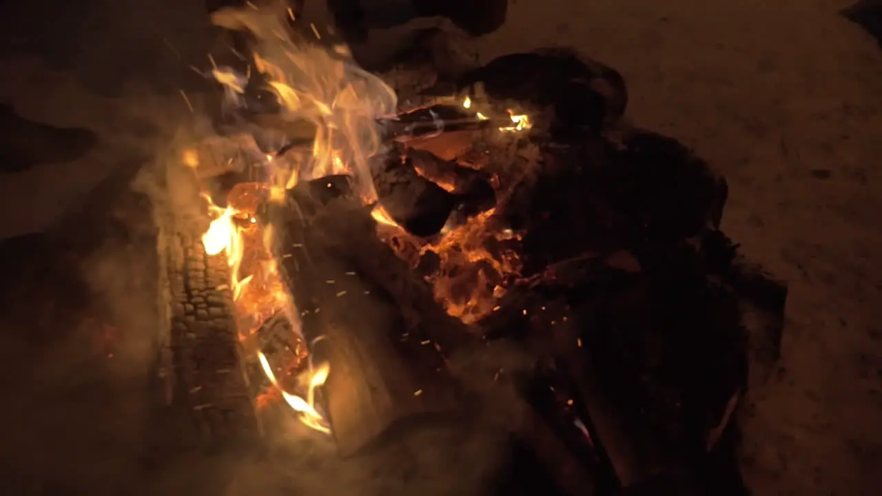 Woman mending the fire outdoor in winter evening