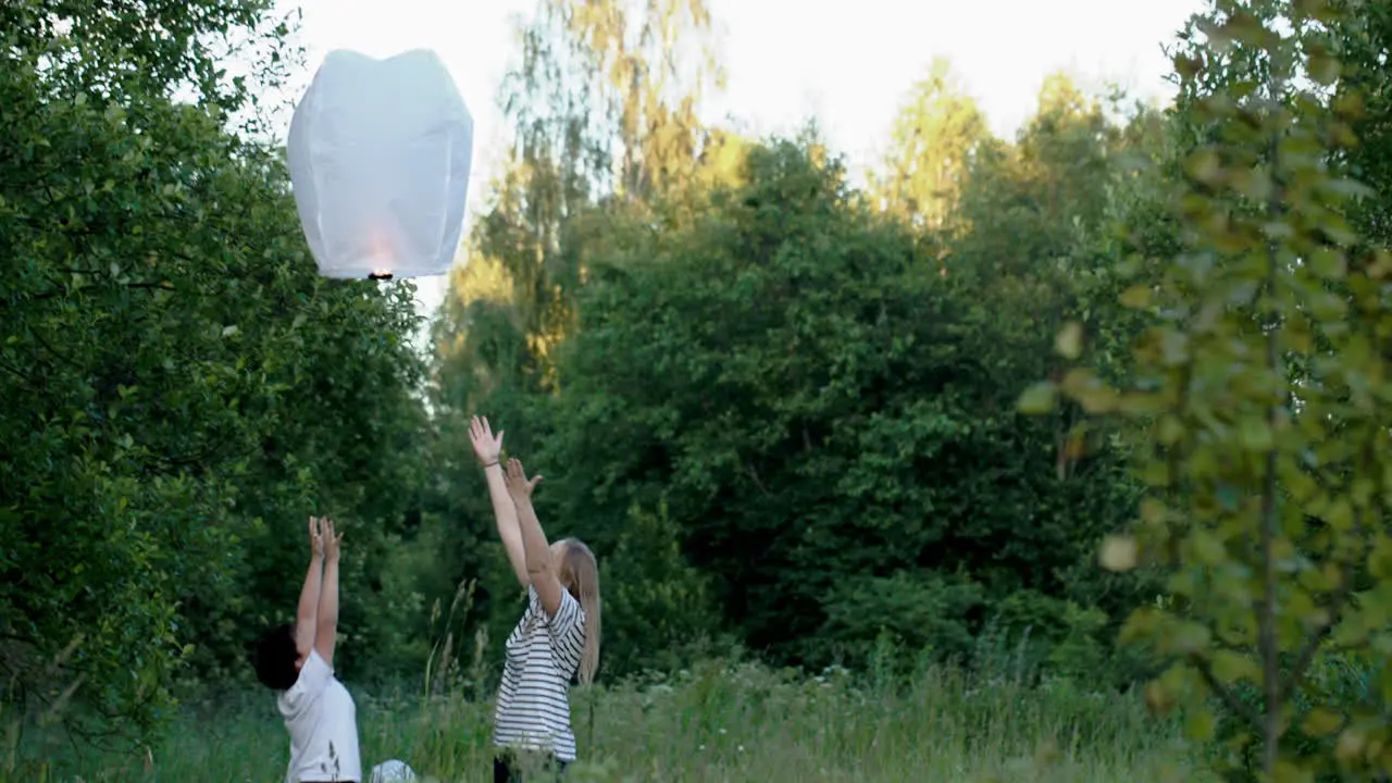 Family flying a fire lantern in the woods