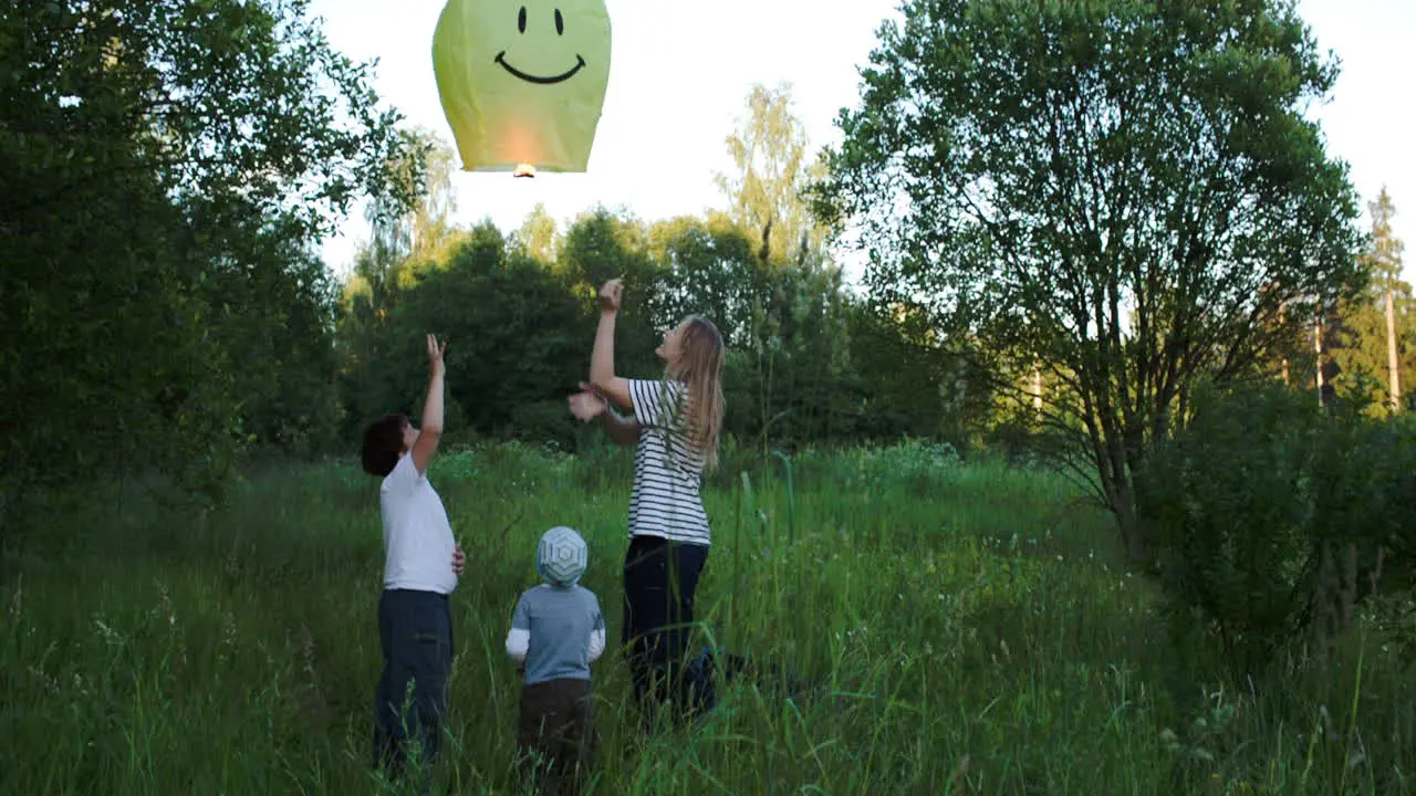 Mother with two sons flying smiling fire lantern