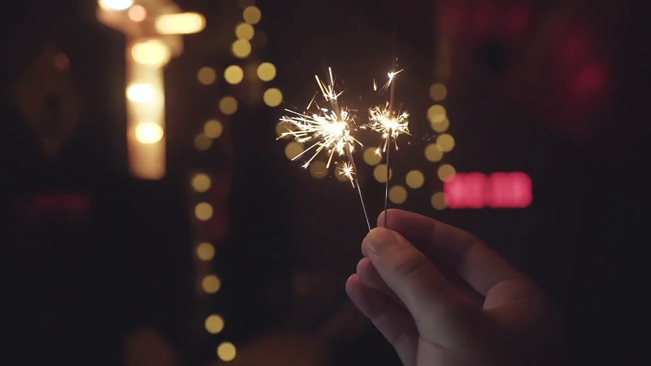 Bright sparklers burning down in slow motion in the dark with lights with bokeh and blurred background