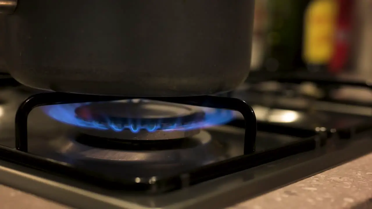 Turning gas stove up with pot on top close up slow motion