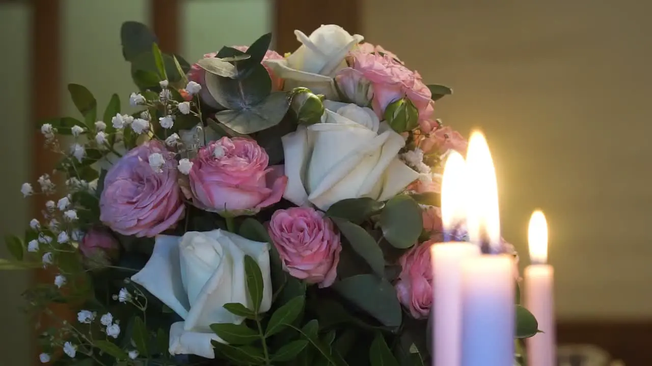 Close up of burning candles on the background of a bouquet of flowers