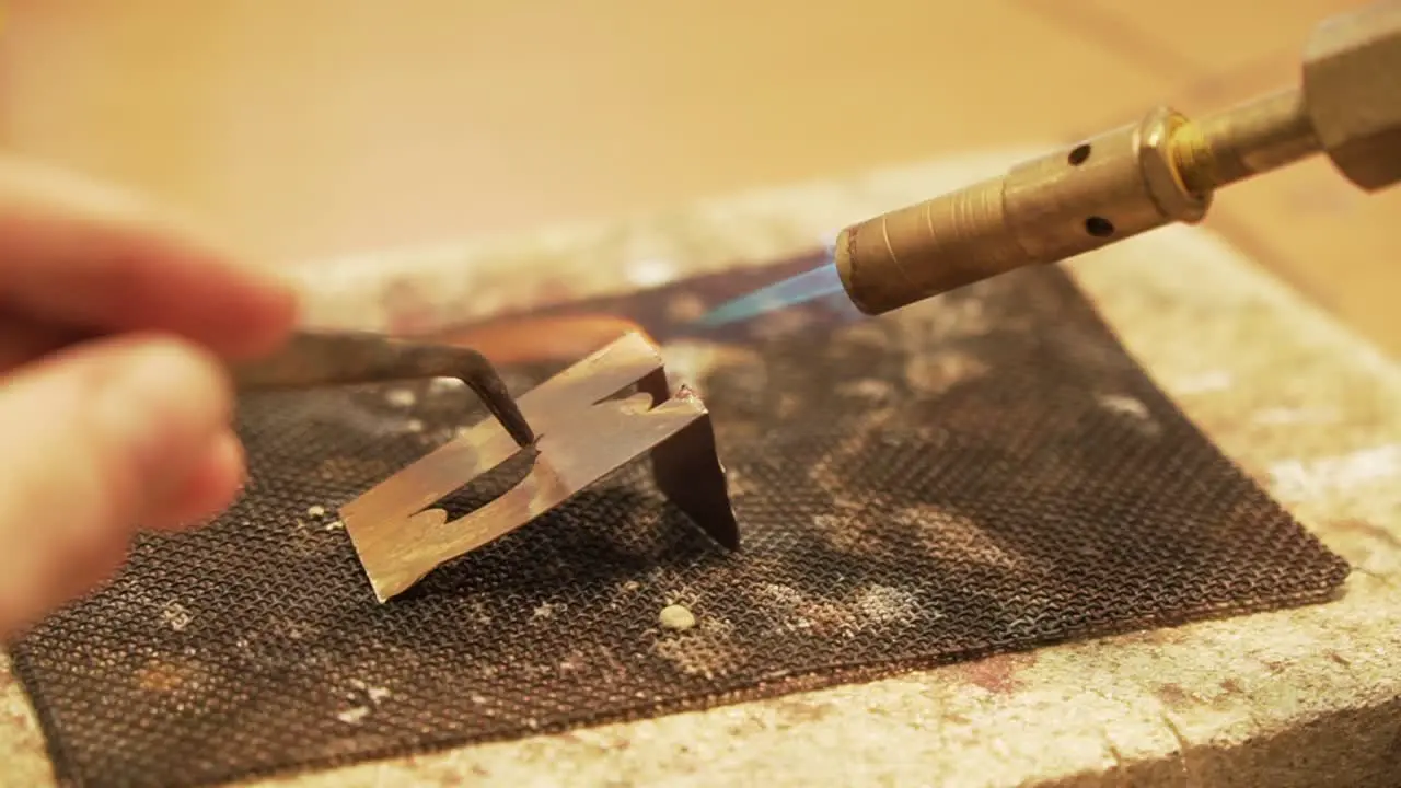 Soldering metal plates with butane gas flame burner close up shot in slow motion