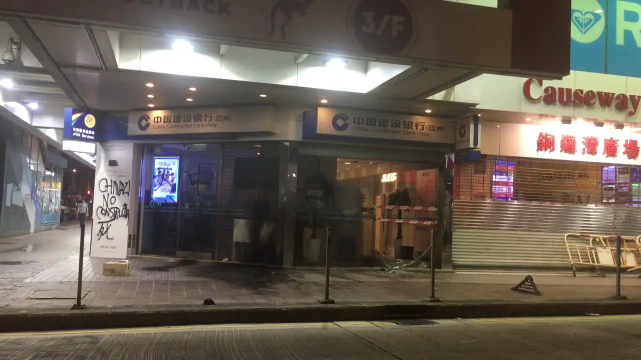 People walking past the destroyed storefront of a Bank in Causeway Bay Hong Kong