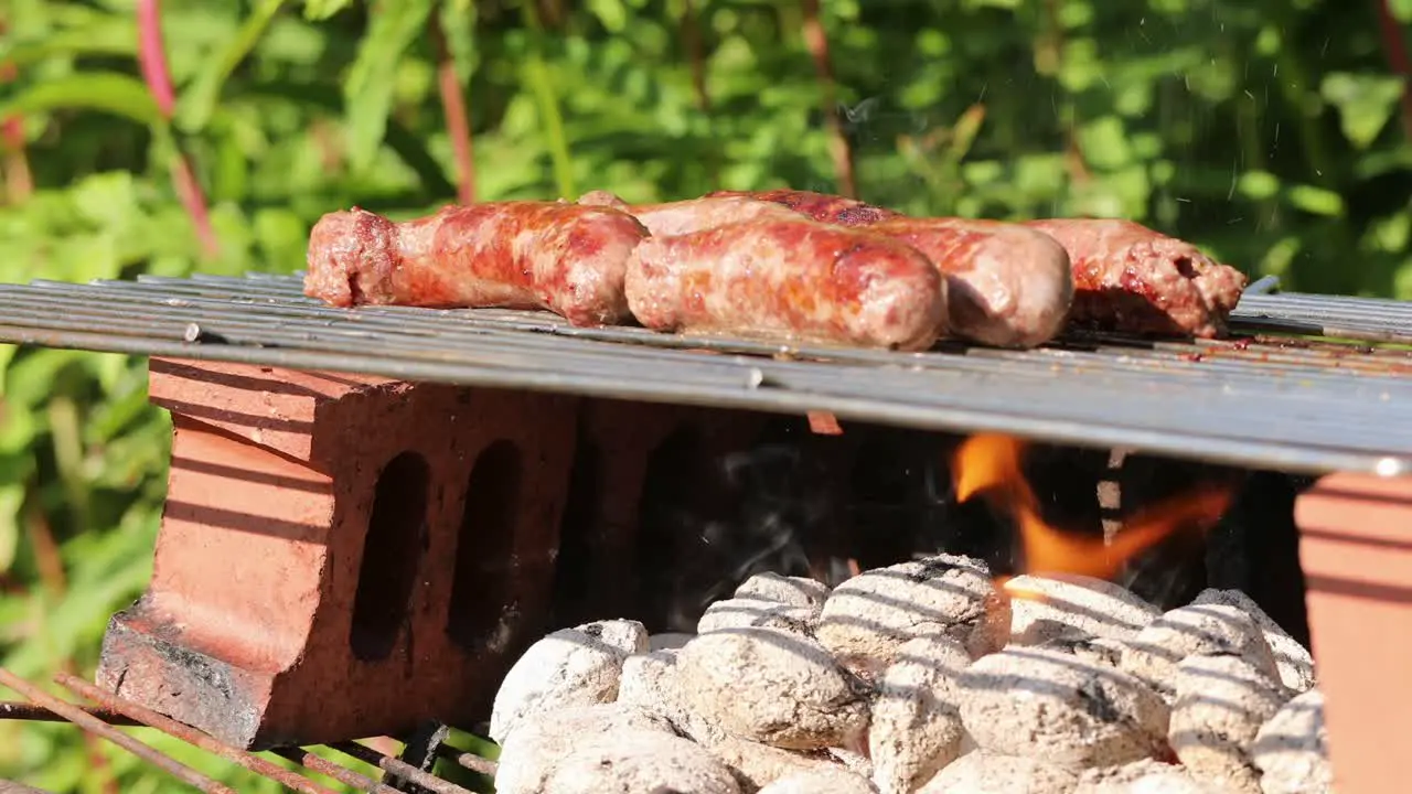 Sausages sizzling on barbecue over hot coals