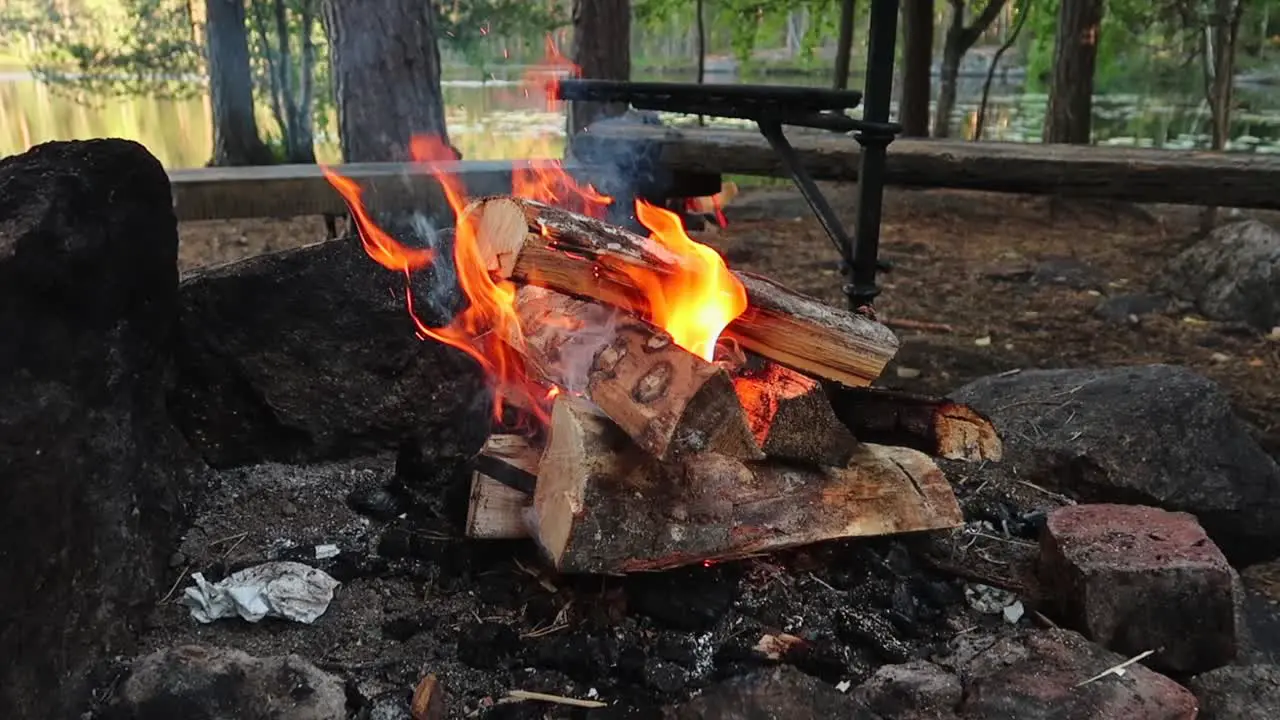 small fire made of wood starting to burn slowly in a rock firepit in Nuuksio National Park in Finland