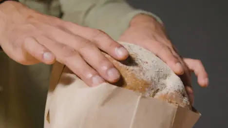 Tracking Shot of a Young Man Unpacking Bread and Smiling