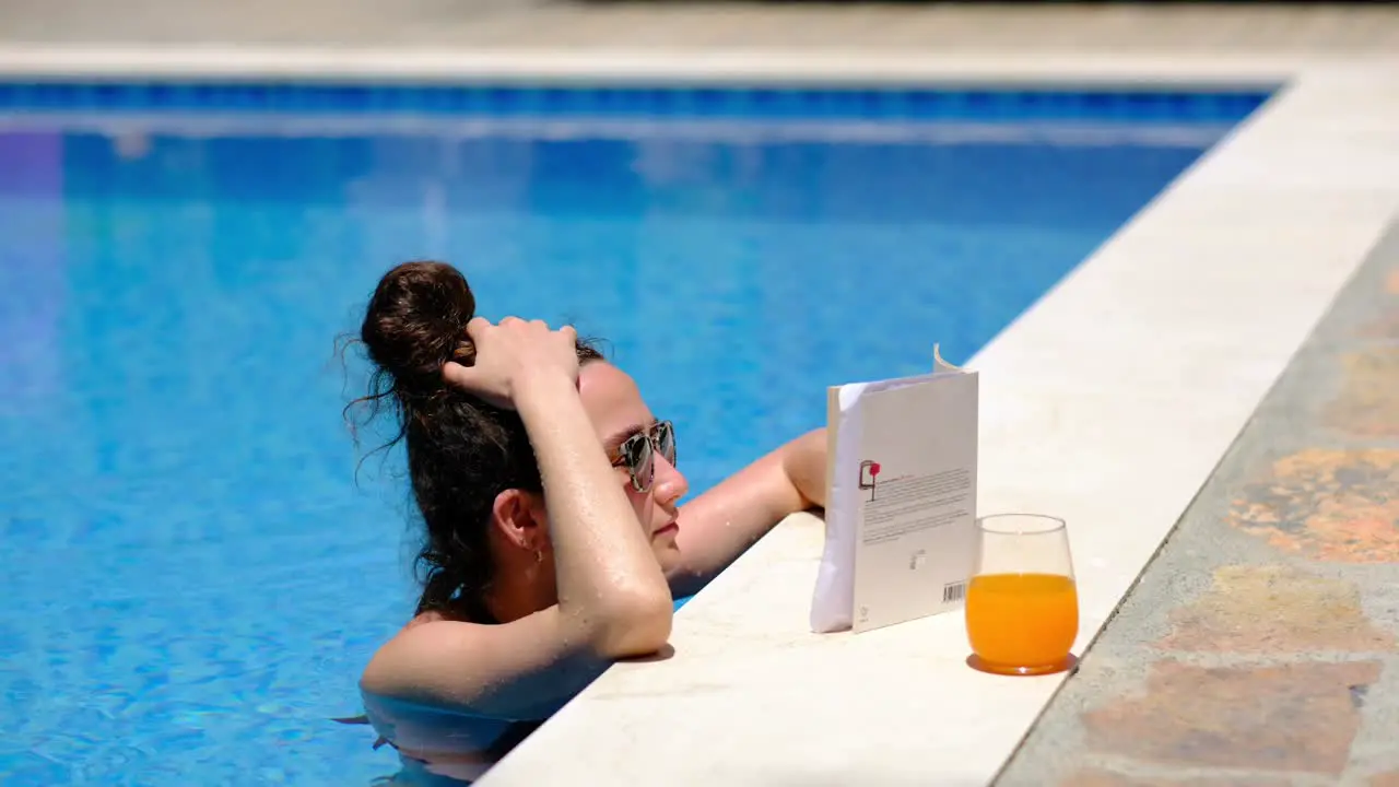 a woman is reading a book by the pool