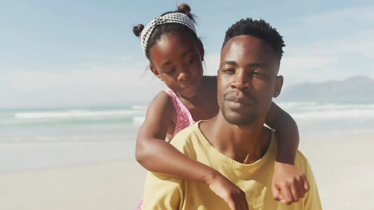 African american daughter hugging her father from behind at the beach