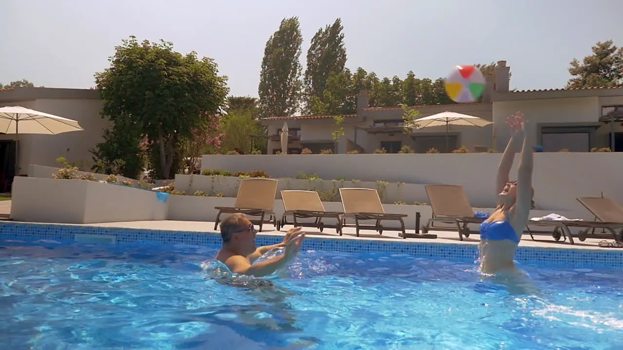 Man and woman playing with ball in the pool