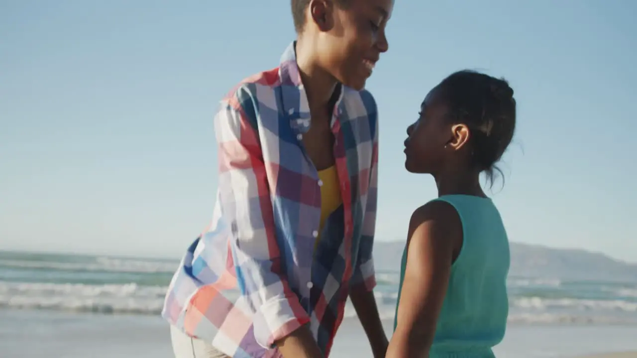 African american mother and daughter hugging each other at the beach