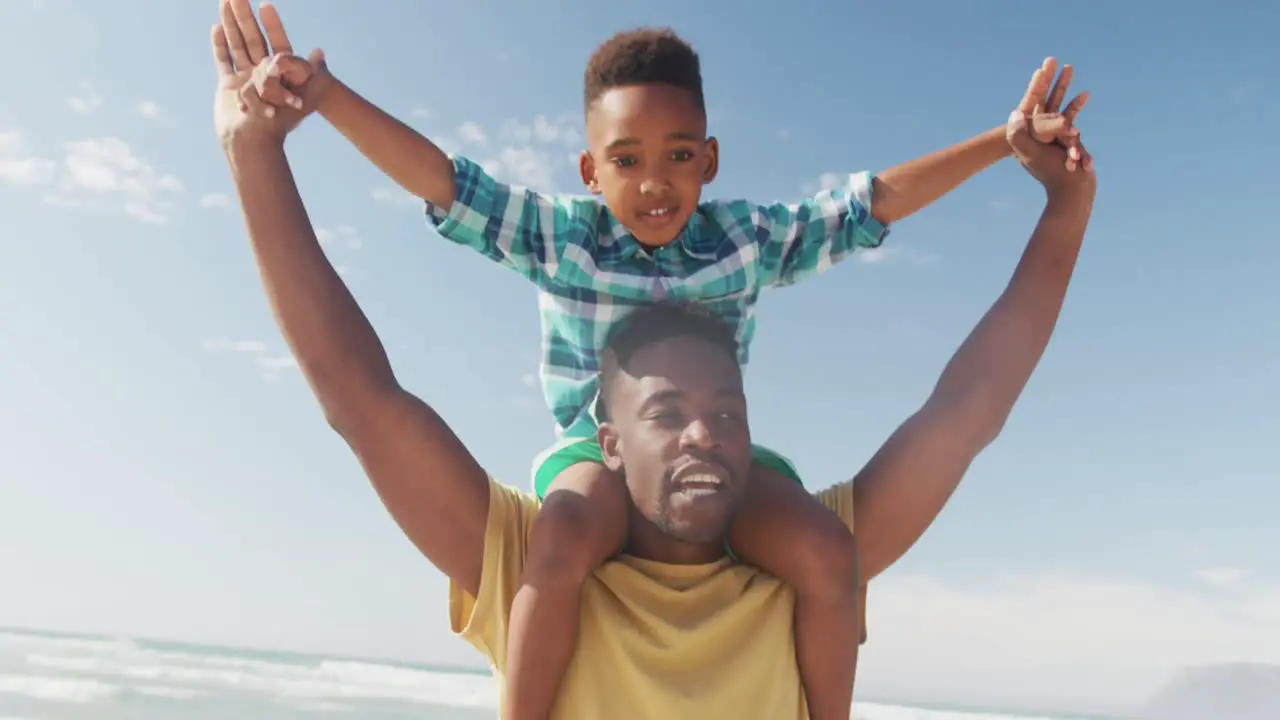 African american father carrying his son on his shoulders at the beach