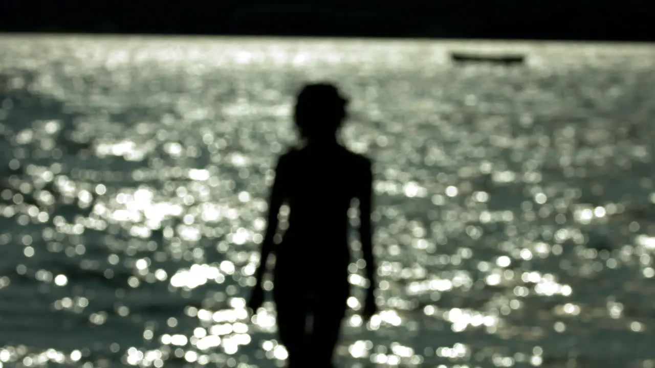 Defocused shoot of siluette of woman standing against lake on sunny weather