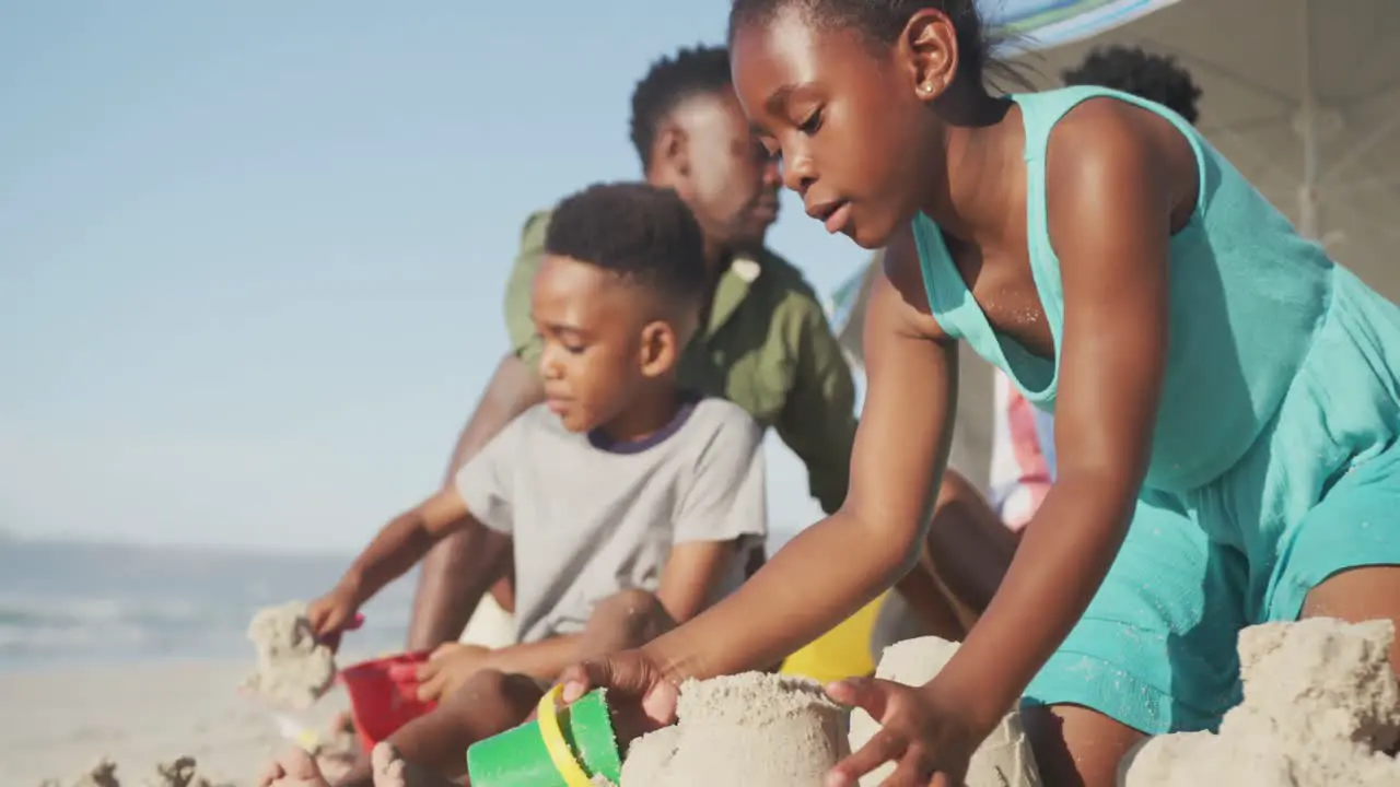 African american brother and sister playing with sand on the beach