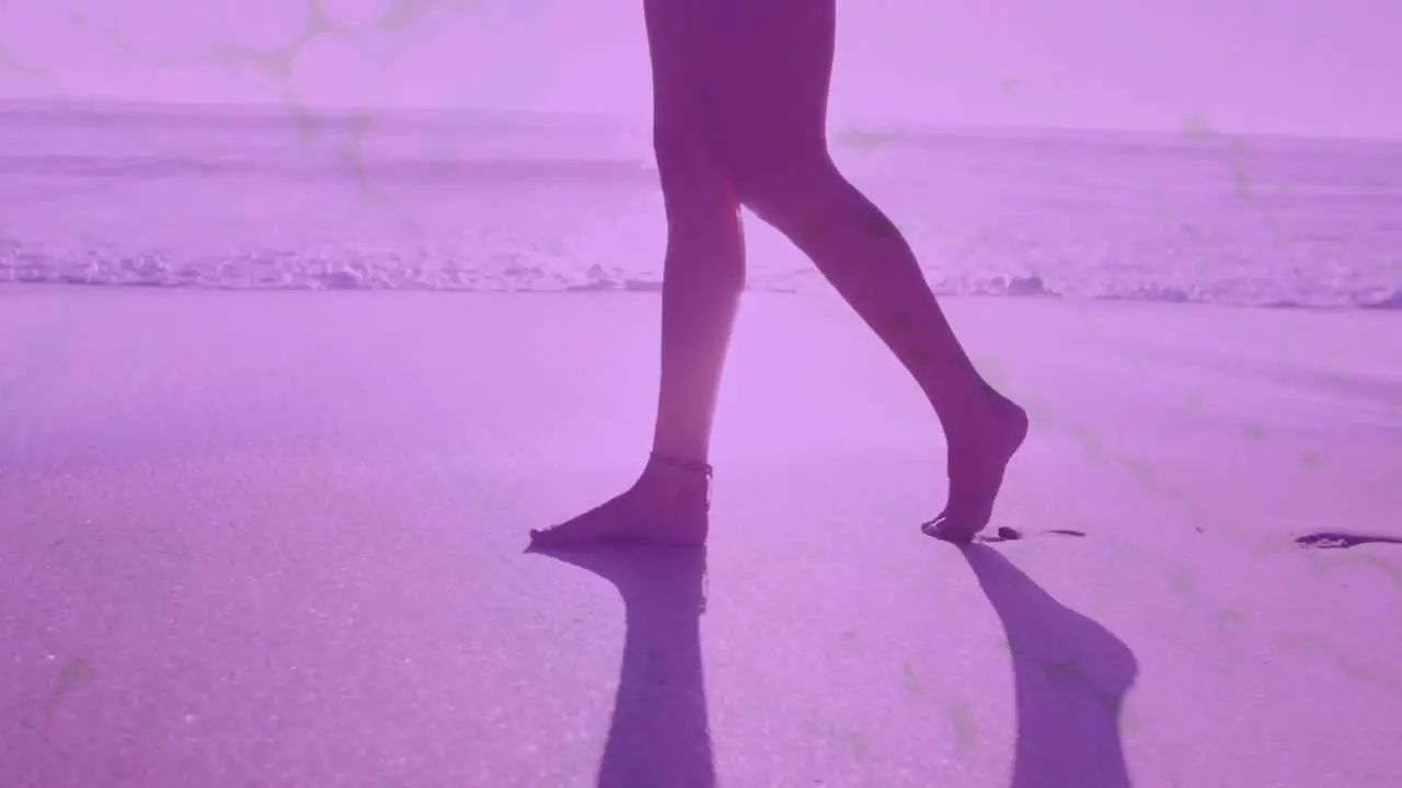 Digital waves against low section of woman walking on the beach