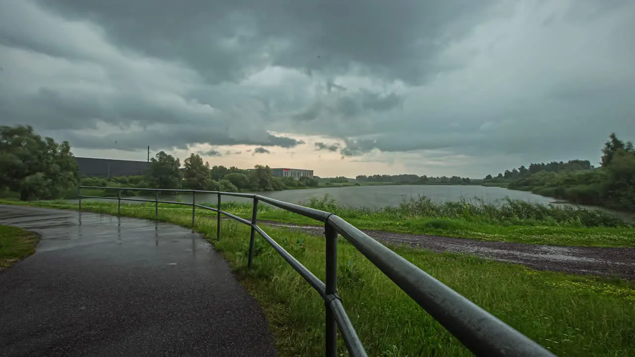 Cloudy Sky Over Calm Lake And Empty Rural Road On A Rainy Weather