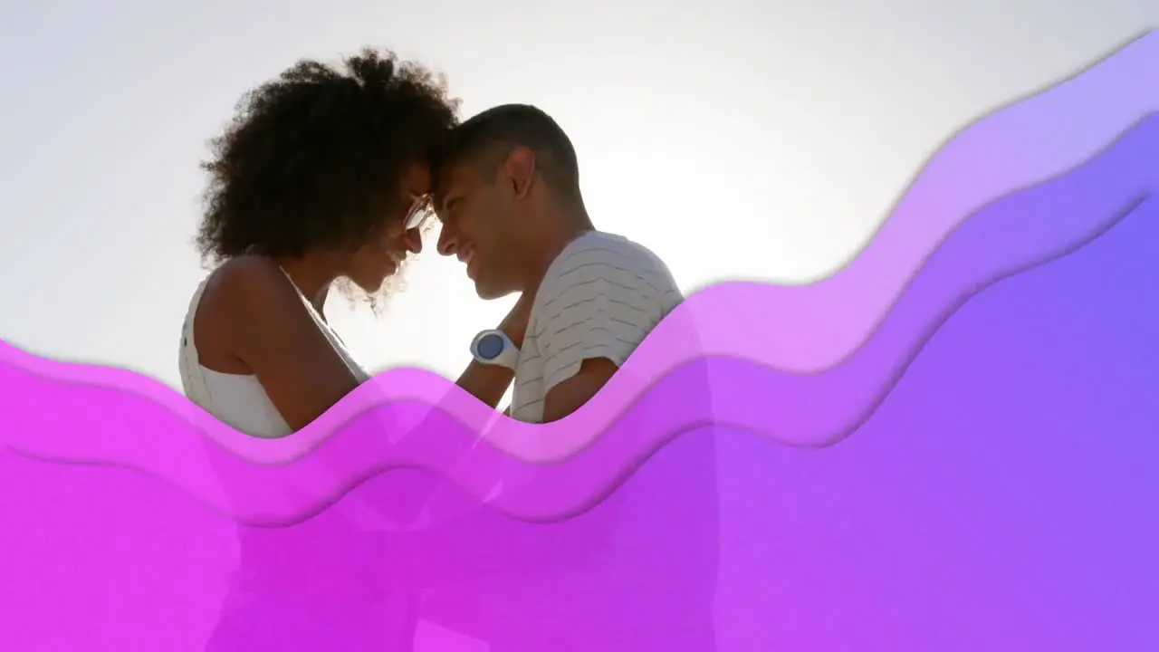 Purple wavy lines against mixed race couple dancing at the beach