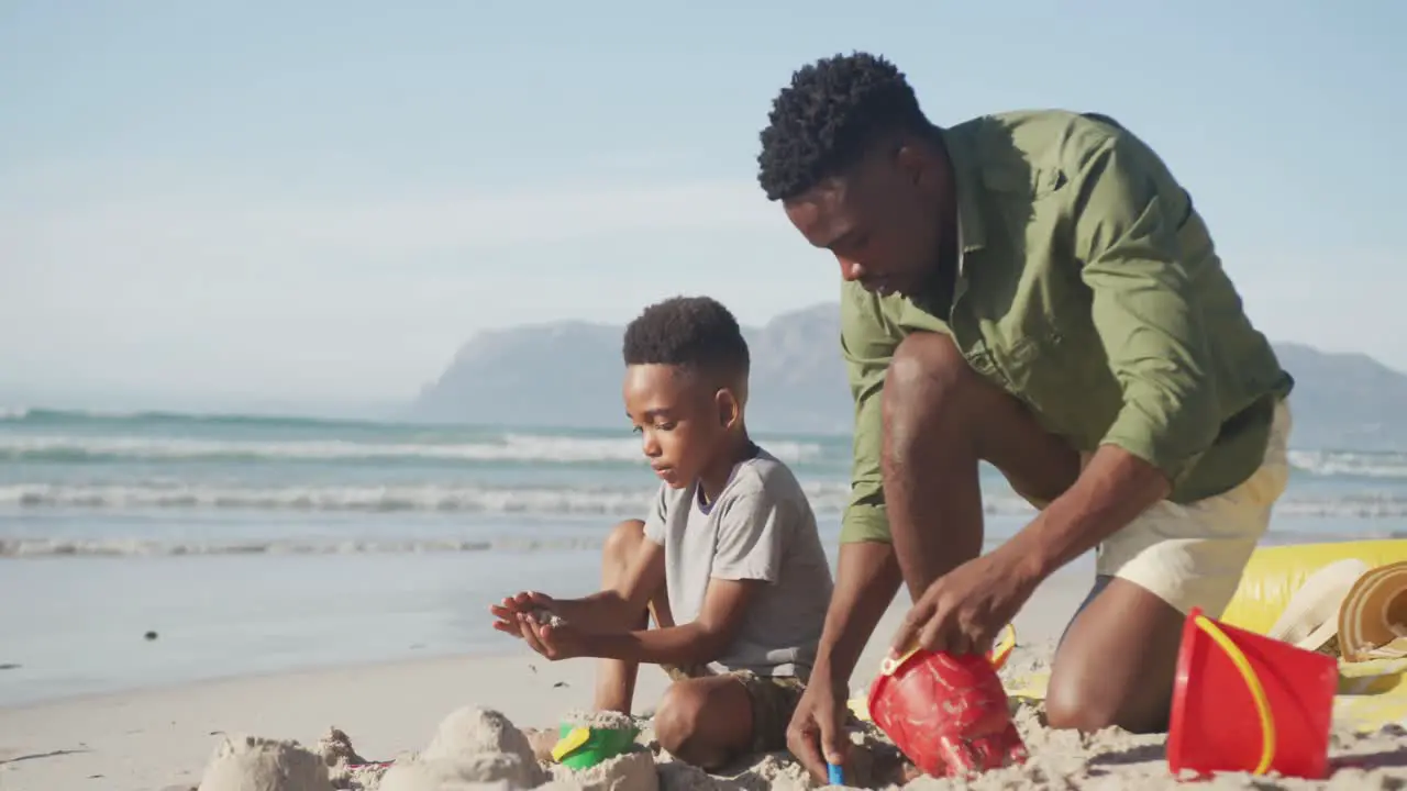 African american father and son playing in the sand on the beach