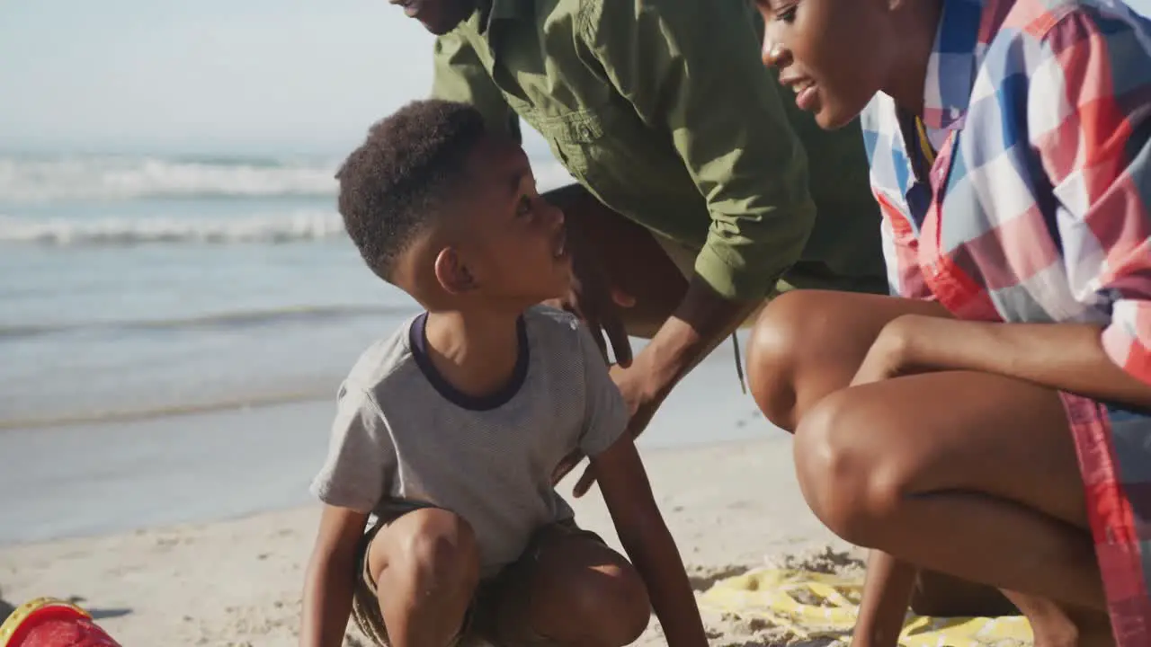 African american couple playing with their son in the sand on the beach