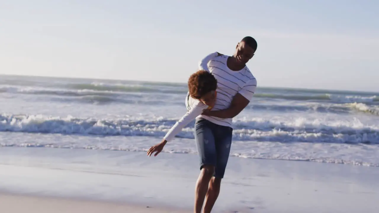 African american father picking up his son and playing at the beach