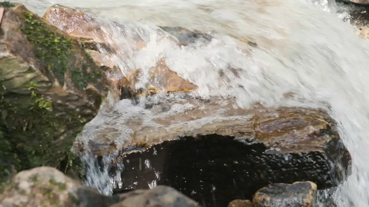 Shallow depth of field dolly side shot of water flowing in springtime down a rapid stream