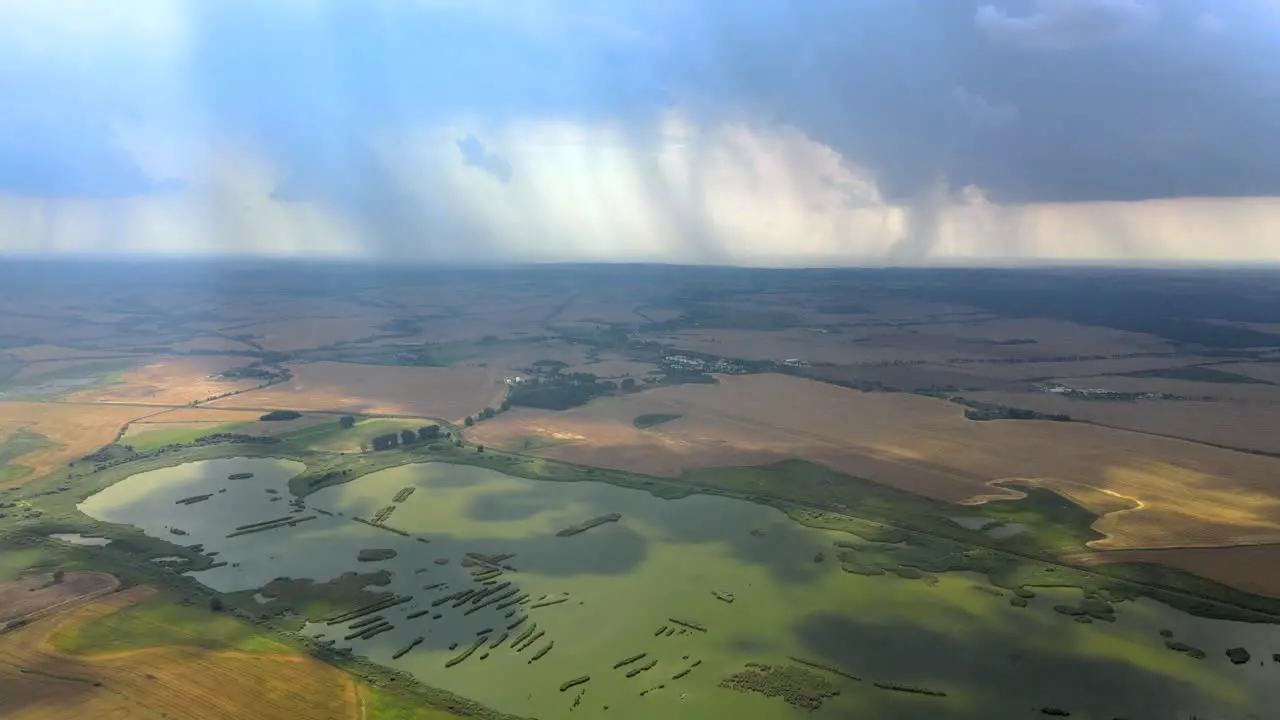 Aerial backward flight over the farm fields and wetlands during the storm