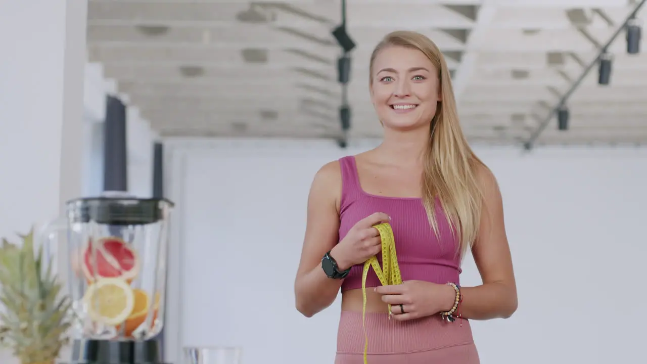 A young beautiful caucasian woman smiles at the camera holding the tape measure a healthy living concept